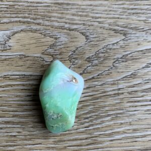 Green and white gemstone on wood.