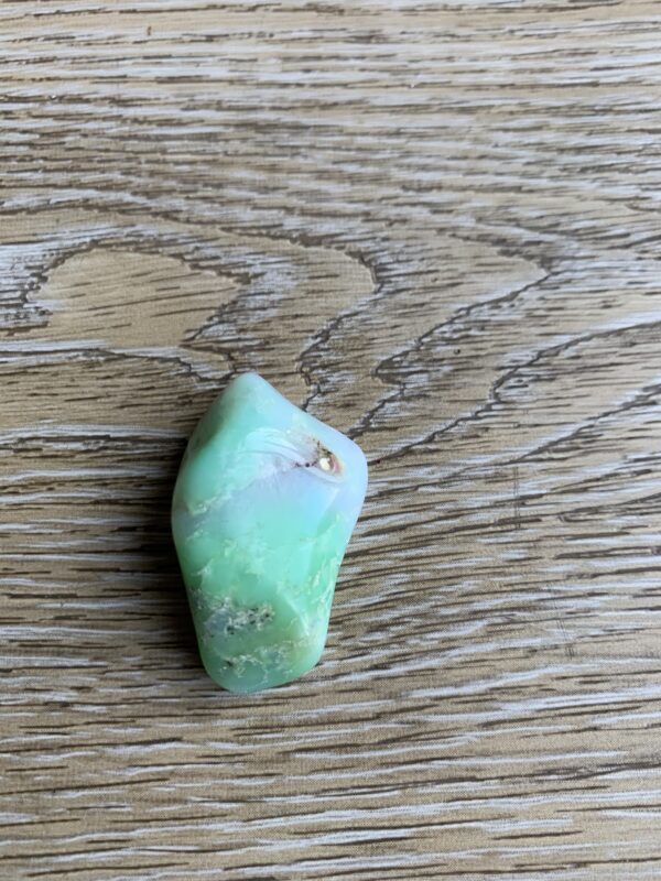 Green and white gemstone on wood.