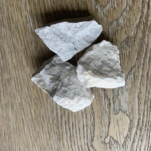 Three white rocks on woodgrain surface.