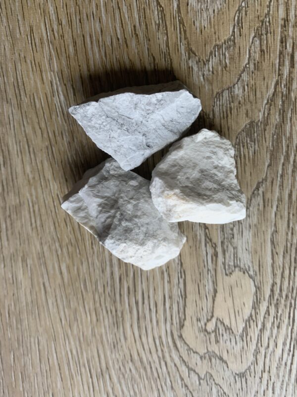 Three white rocks on woodgrain surface.