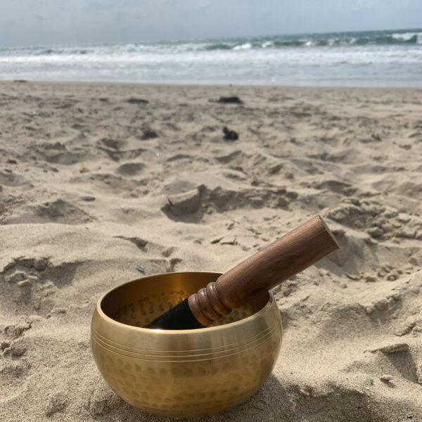 Golden singing bowl on a sandy beach.