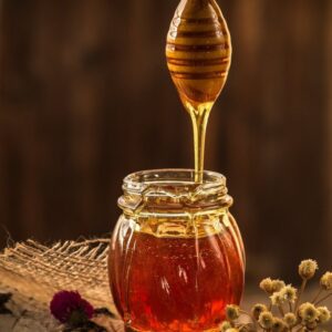 Honey dripping into a glass jar.