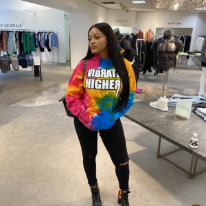 Woman wearing tie-dye hoodie in store.