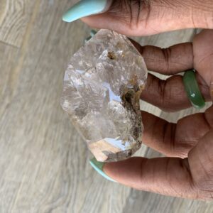 Hand holding a clear quartz crystal.