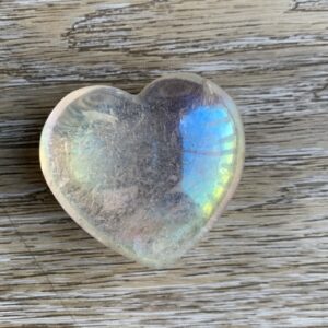 Clear heart-shaped crystal on wood grain.