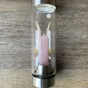 Rose quartz crystal in a glass water bottle.