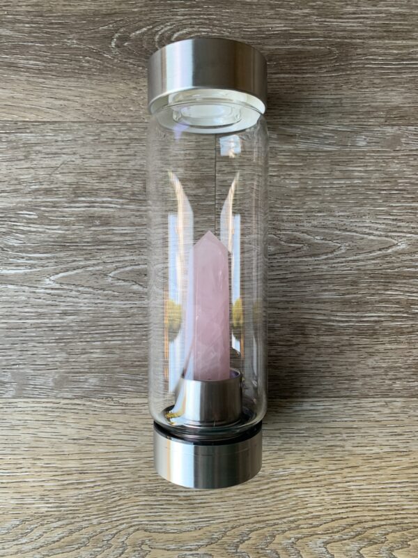 Rose quartz crystal in a glass water bottle.