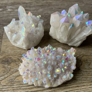 Three iridescent quartz crystals on wood.