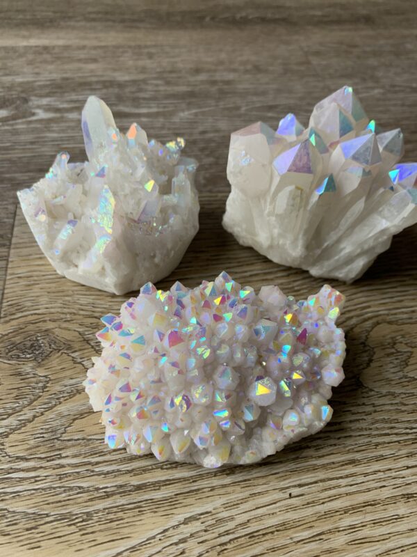 Three iridescent quartz crystals on wood.