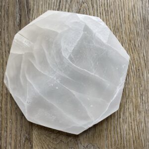 White selenite crystal on wood background.