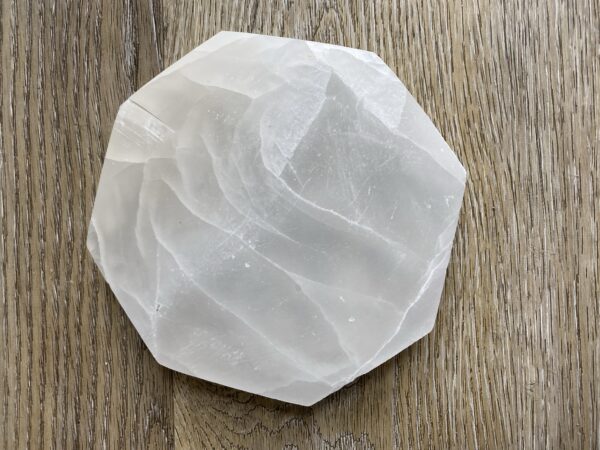 White selenite crystal on wood background.