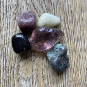 Five colorful gemstones on wood background.