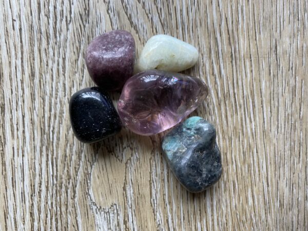 Five colorful gemstones on wood background.