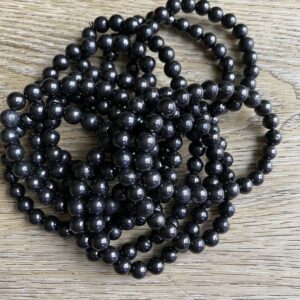 Black round beads on wooden surface.