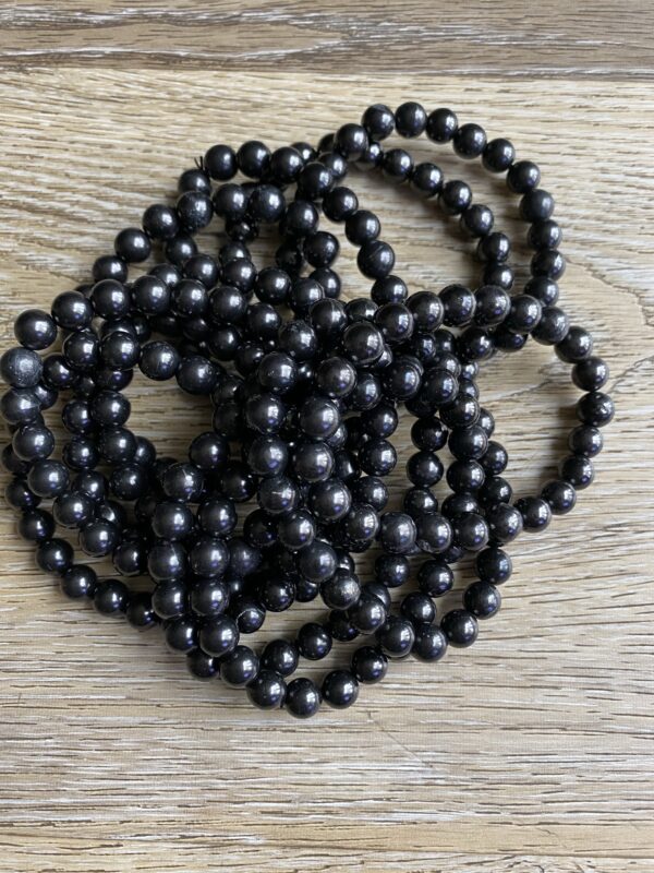 Black round beads on wooden surface.