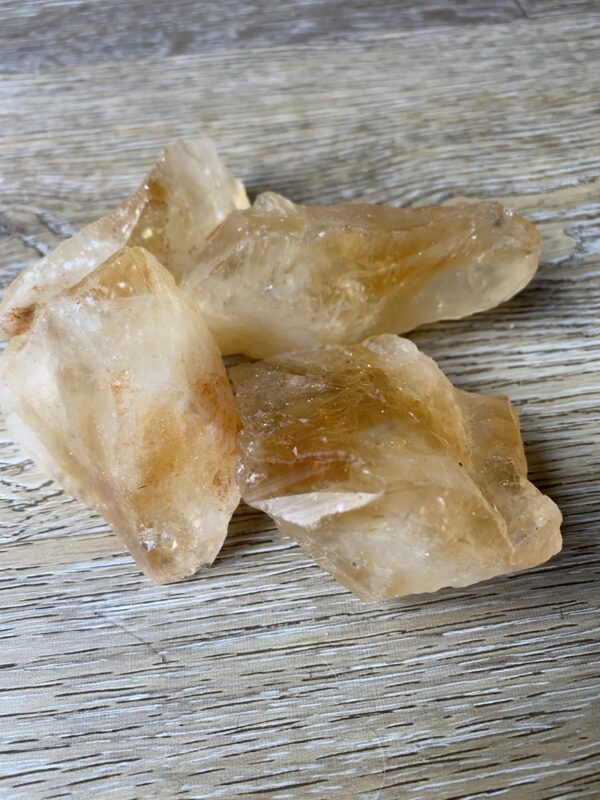 Three raw citrine crystals on wood.