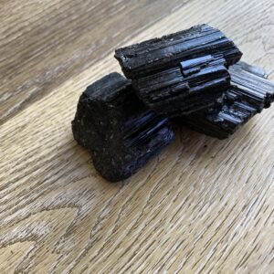 Black tourmaline crystals on wood surface.