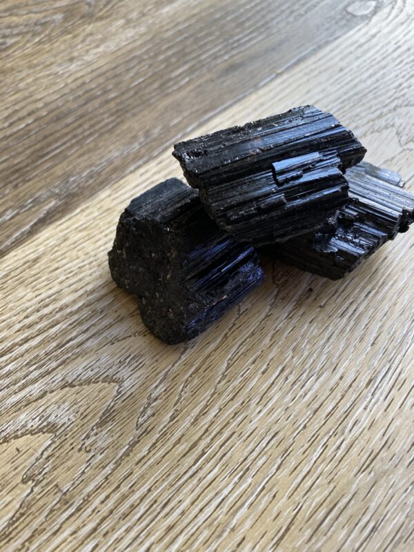 Black tourmaline crystals on wood surface.