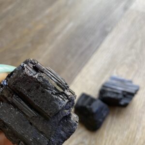 Black tourmaline crystal on wood table.