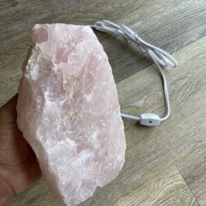 Large pink quartz crystal lamp on wood floor.