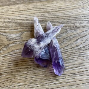 Three purple amethyst crystals on wood.