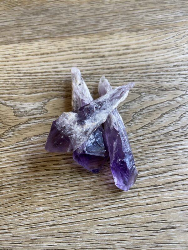 Three purple amethyst crystals on wood.