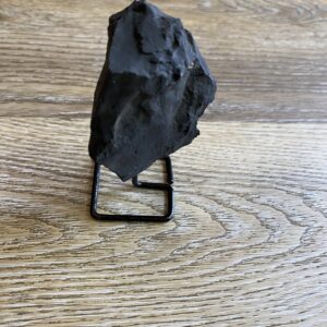 Black rock on metal stand on wood.