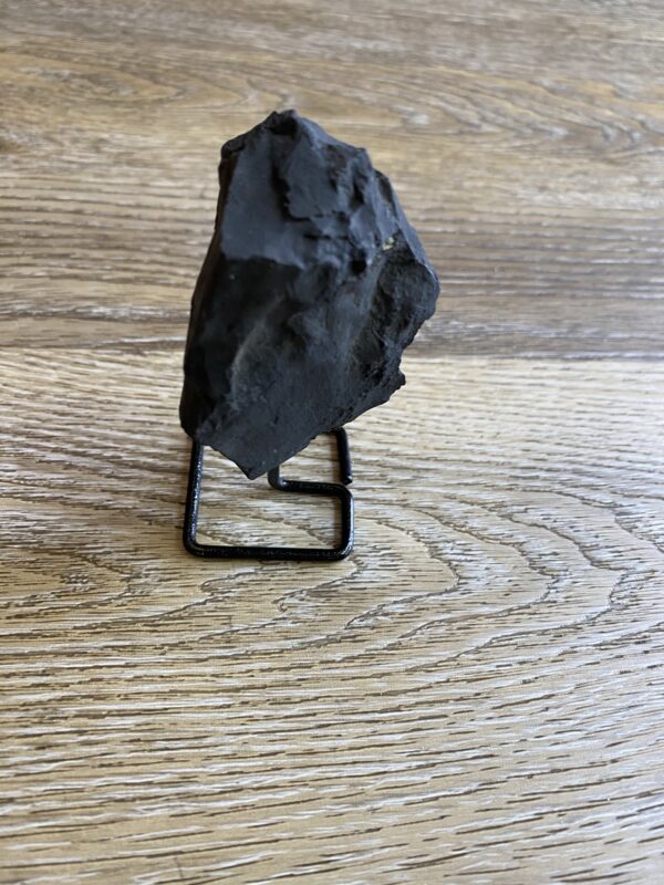 Black rock on metal stand on wood.