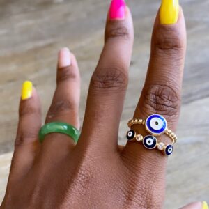 Hand with green and evil eye rings.