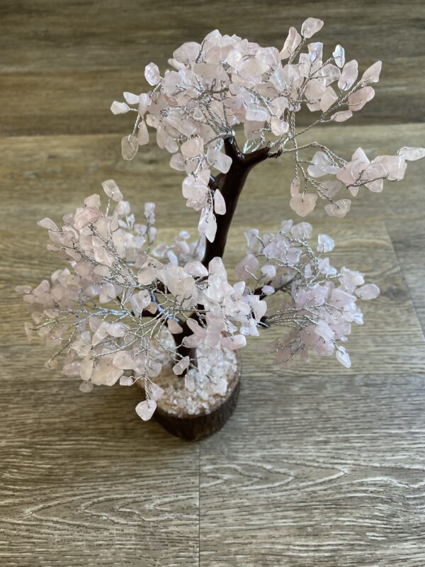 Pink crystal wire-wrapped tree on wood.