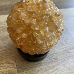 Citrine crystal sphere on wooden table.