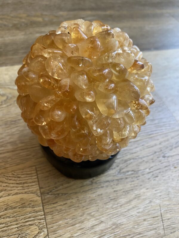 Citrine crystal sphere on wooden table.