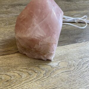 Pink crystal pyramid lamp on wood table.