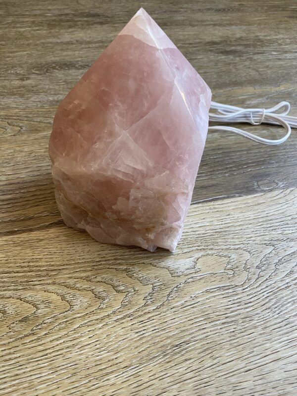 Pink crystal pyramid lamp on wood table.