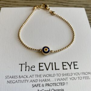 Gold evil eye bead bracelet on white card.