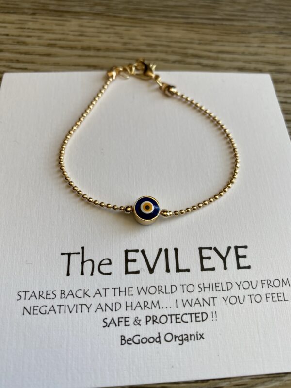 Gold evil eye bead bracelet on white card.