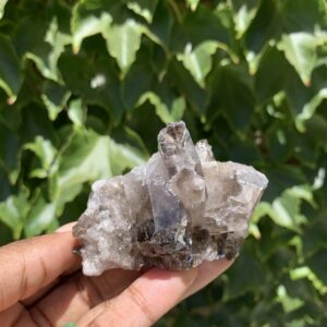 Smoky quartz crystal cluster in hand.