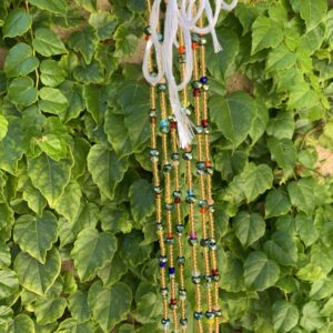 Multicolored beaded necklace against green leaves.