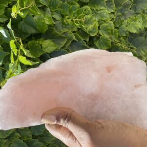 Hand holding a large pink crystal.