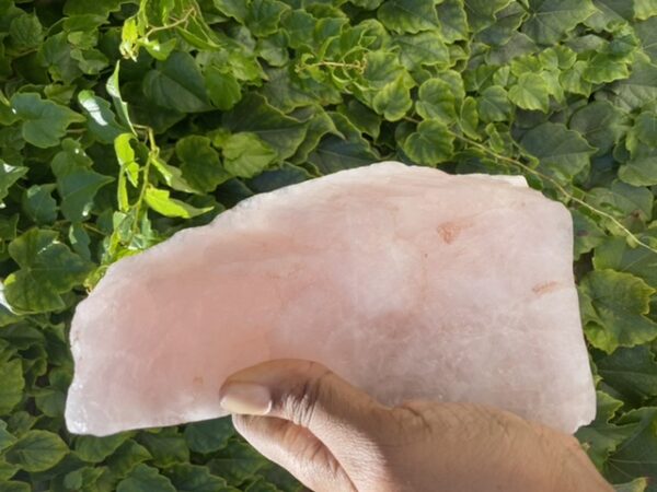 Hand holding a large pink crystal.