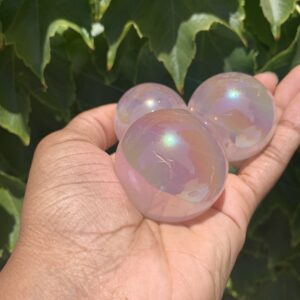 Three iridescent crystal spheres in hand.