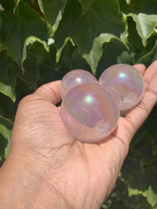 Three iridescent crystal spheres in hand.