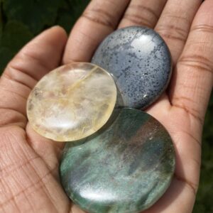 Three round polished gemstones in hand.