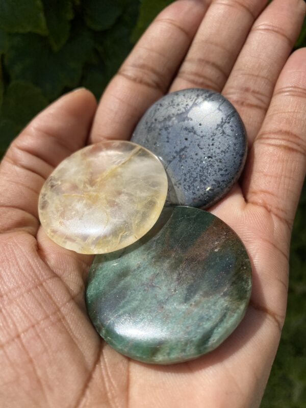 Three round polished gemstones in hand.