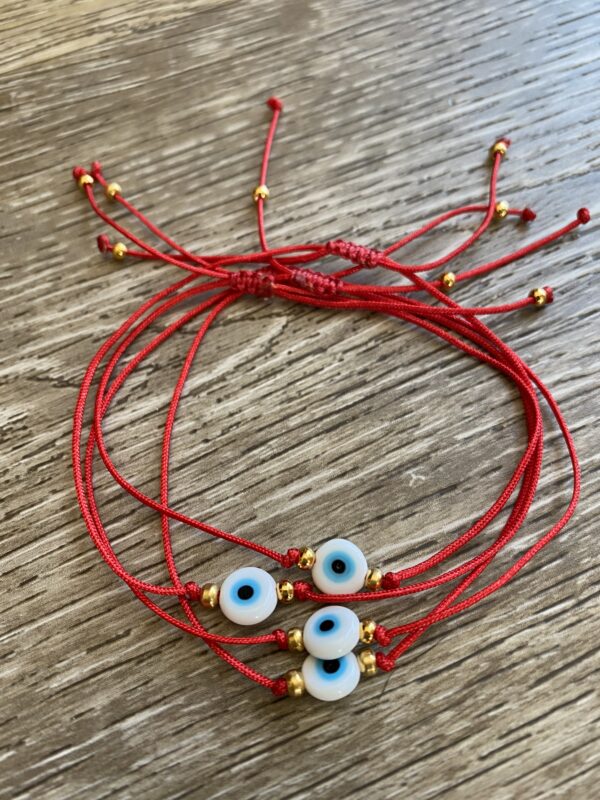 Red string bracelets with blue evil eyes.