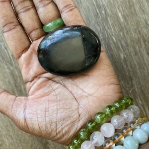 Black obsidian palm stone in hand.