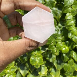 Hand holding a pink hexagonal crystal.