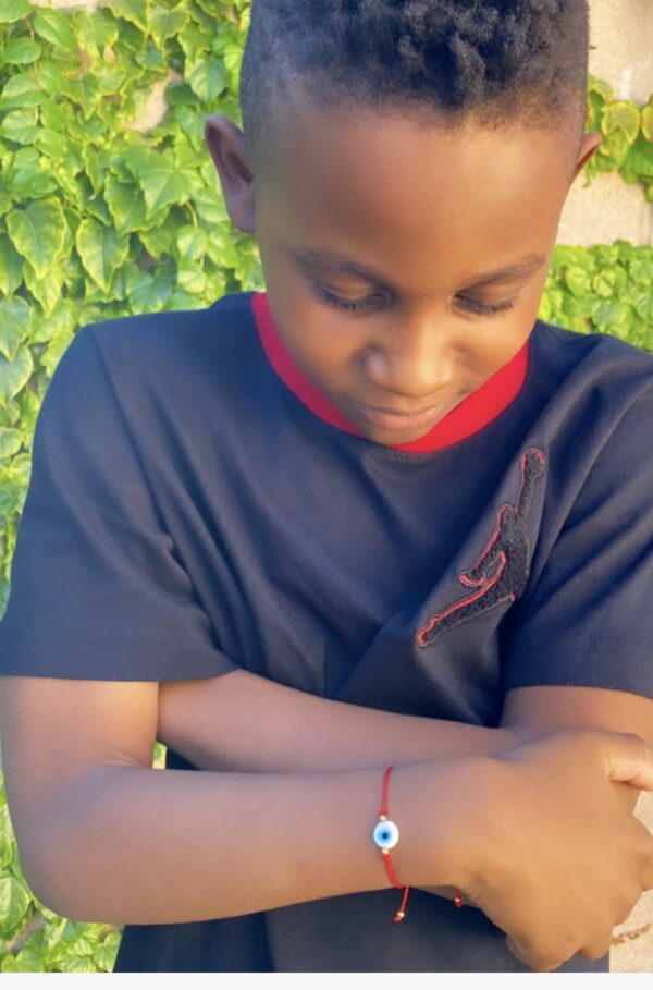 Boy wearing a red string bracelet with evil eye charm.