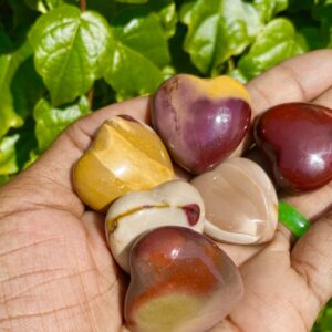 Five heart-shaped polished stones in hand.