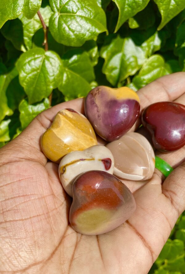 Five heart-shaped polished stones in hand.